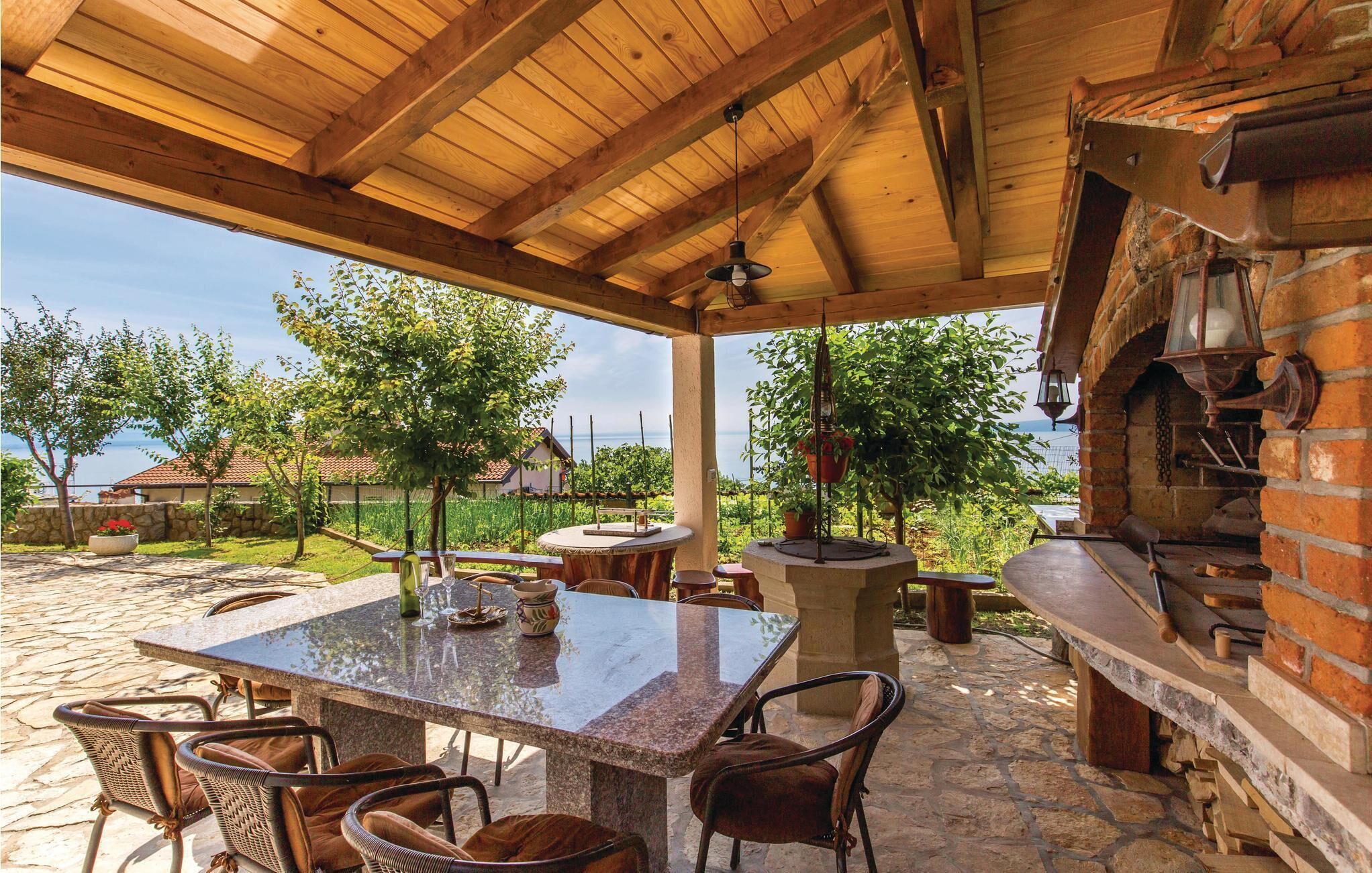 Un patio al aire libre con una mesa de piedra, sillas y un horno de ladrillo.