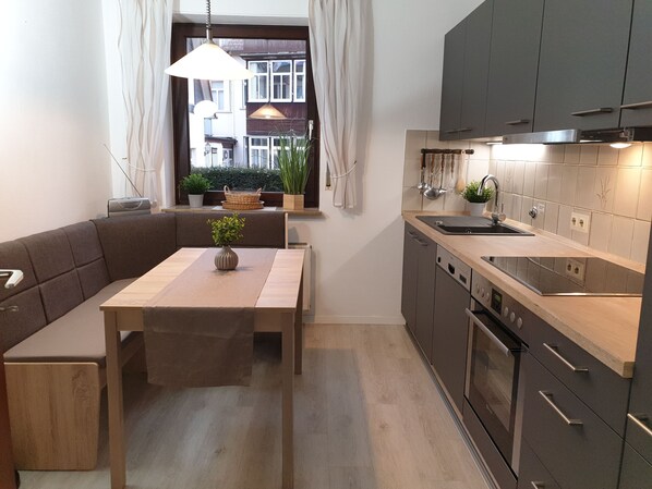 Une cuisine moderne avec un coin repas, des appareils électroménagers intégrés et une vue sur la rue.