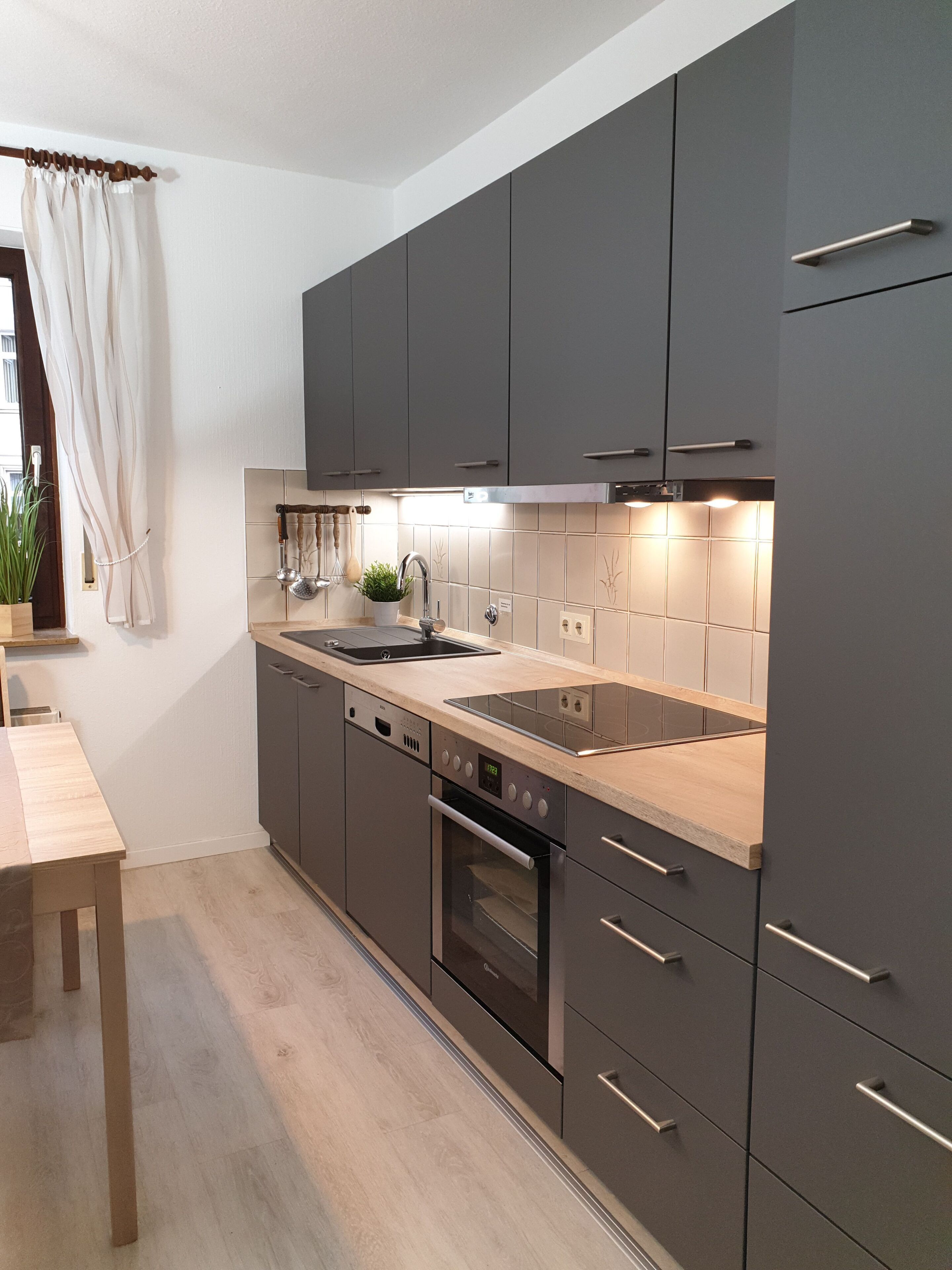 A modern kitchen with dark cabinets, a stainless steel sink, and an oven.