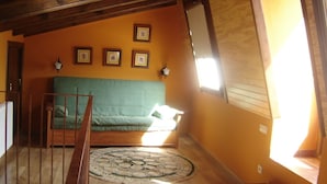 Une pièce avec un plancher en bois, un canapé vert, un tapis à motifs et une rambarde en bois.