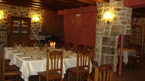 Un restaurant aux murs de pierre, aux tables et aux chaises en bois.