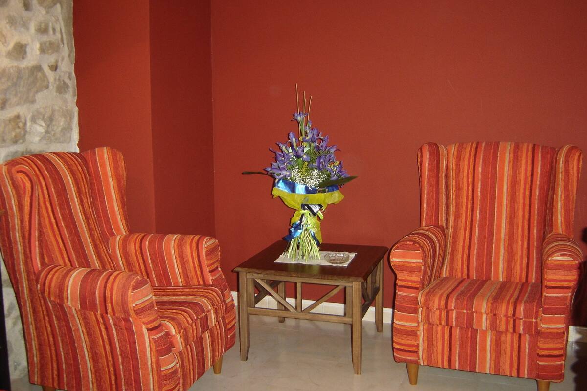Ein Zimmer mit zwei gestreiften Sesseln, einem Holztisch und einer Vase mit Blumen.