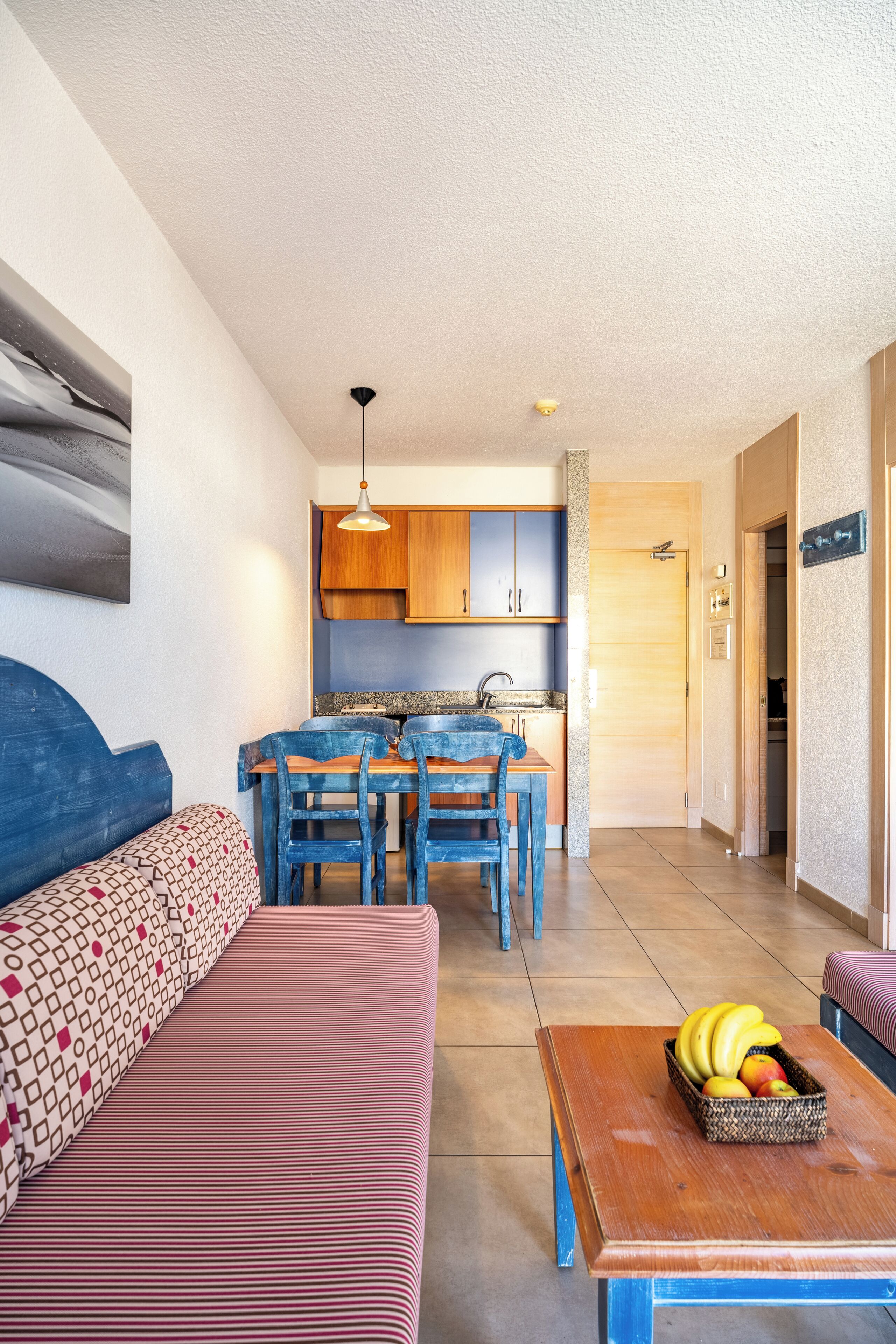 Un espacio habitable compacto con kitchenette, comedor y sofá.