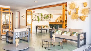 A modern hotel lobby with a sofa, armchairs, and a coffee table. - Cala Nova Apartamentos (Mogan)