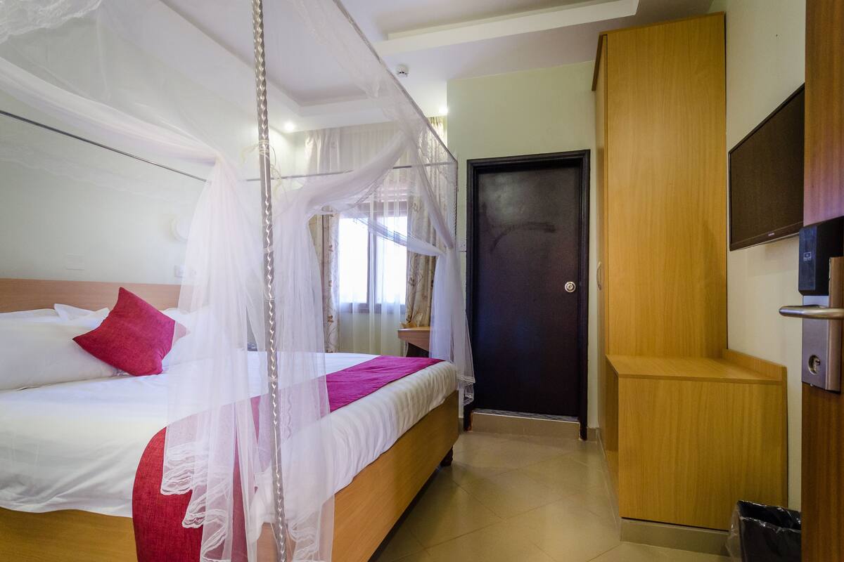 Una habitación de hotel con cama, mesita de noche, armario y puerta.