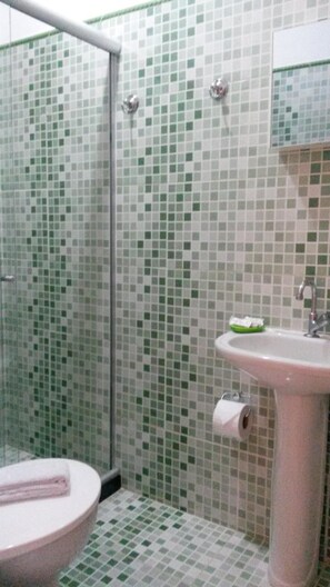 Un baño con inodoro, lavabo y zona de ducha.