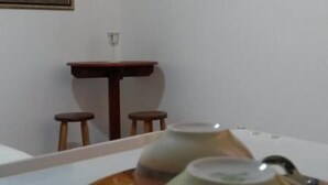 A room with a table, a chair, a television mounted on the wall, and a painting on the wall. - Pousada Melodia do Mar (Cabo Frio)