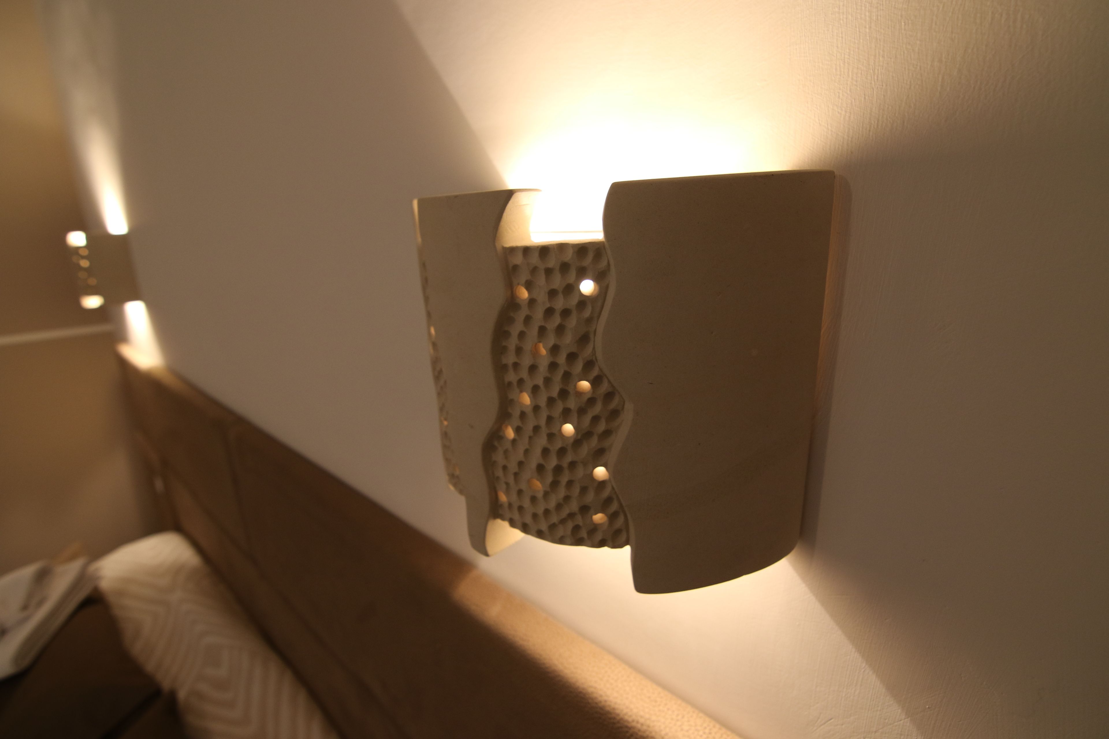 A wall-mounted light fixture with a textured pattern and a wooden frame.