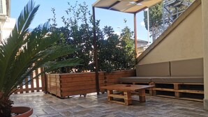 An outdoor patio with a wooden table and benches, surrounded by a stone-tiled floor and a wooden fence. - Casa Dell'Artista (Matera)