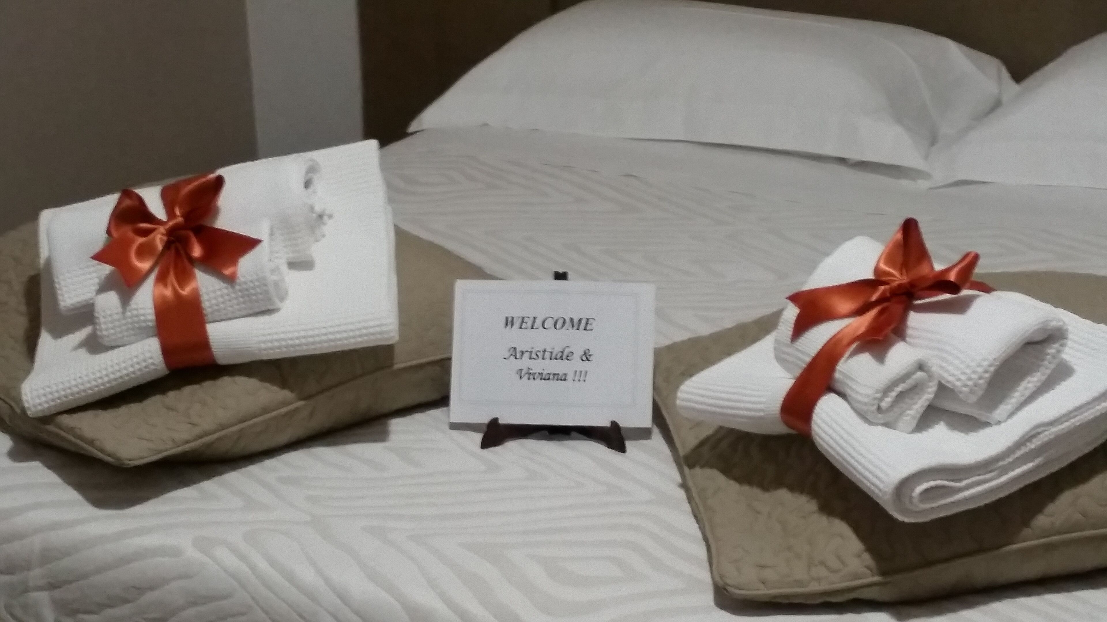 Un lit bien fait, avec des serviettes pliées et un panneau d’accueil.