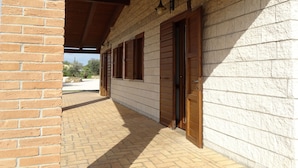 A covered outdoor area with a brick wall, wooden door, and windows. - Agriturismo Podere 1248 (Ladispoli)
