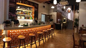 A bar area with a wooden counter, stools, and a variety of bottles. - The Berry Vinhomes Luxury Apartments (Ho Chi Minh City)