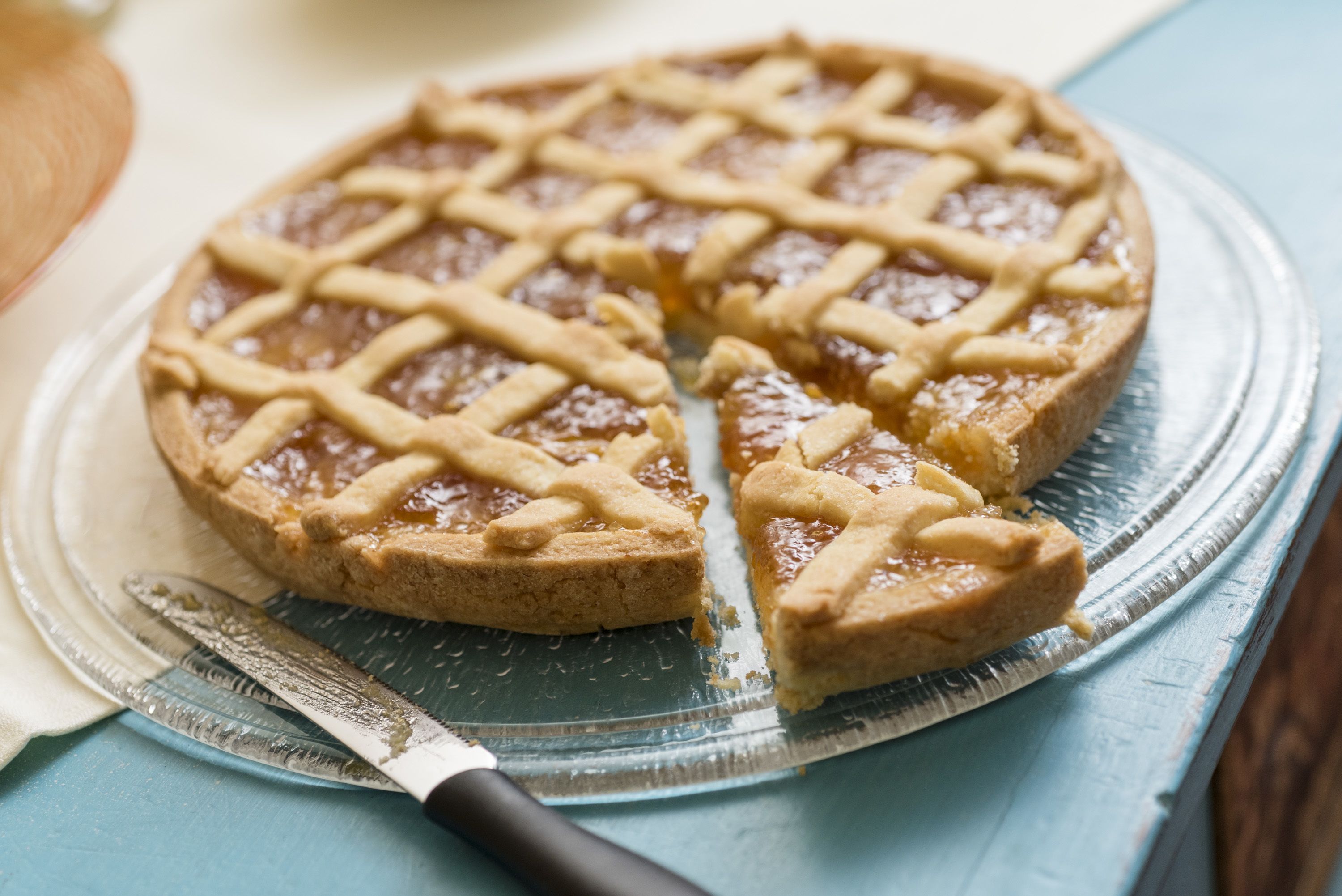 A pie with a lattice crust on a clear glass plate.