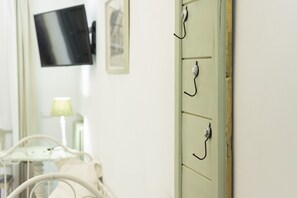 A room with a bed, a television mounted on the wall, and a cabinet with hooks. - Fattoria Pian di Rocca (Castiglione della Pescaia)
