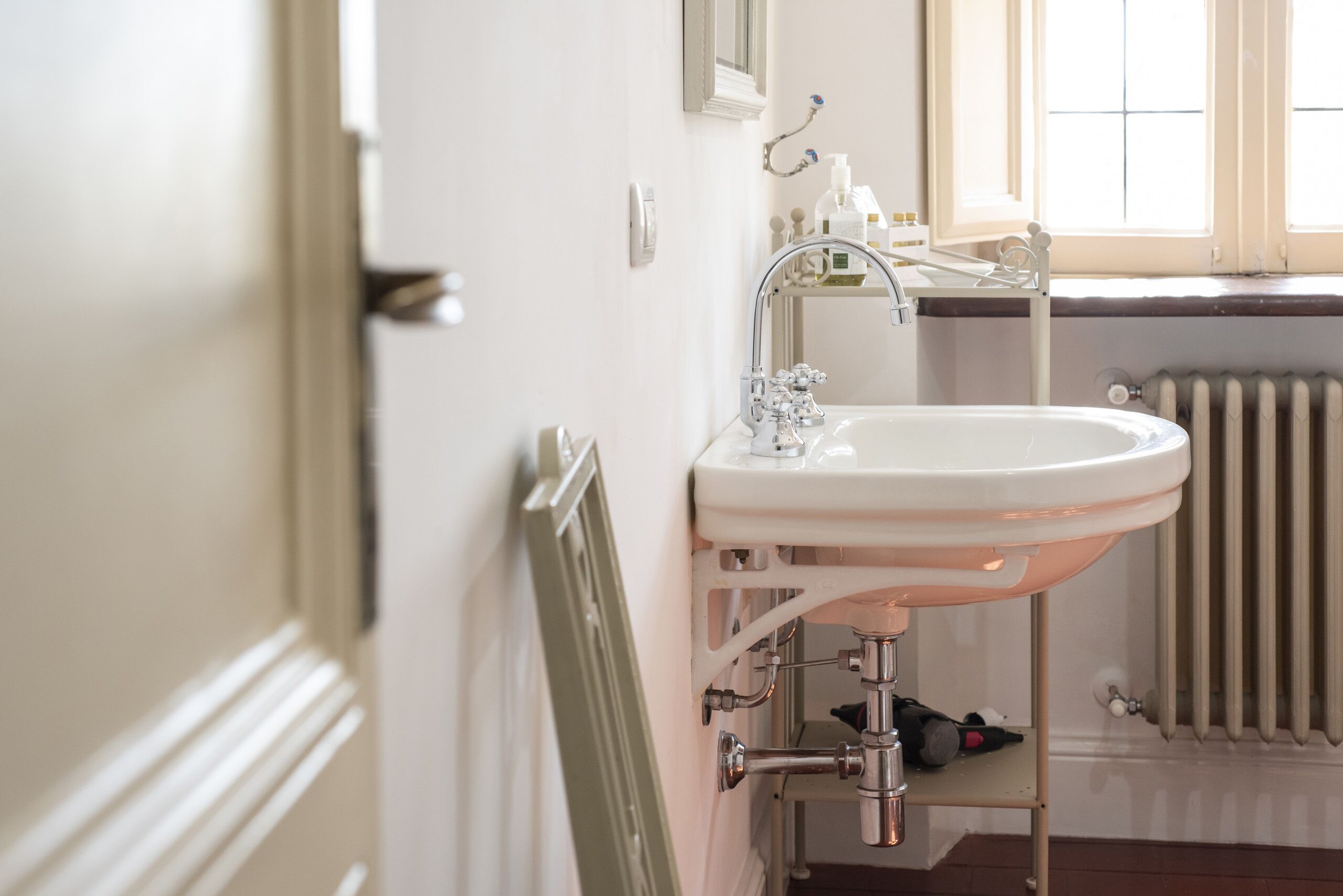 A bathroom with a white sink, a mirror, and a window.