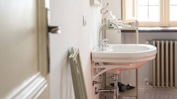A bathroom with a white sink, a mirror, and a window.
