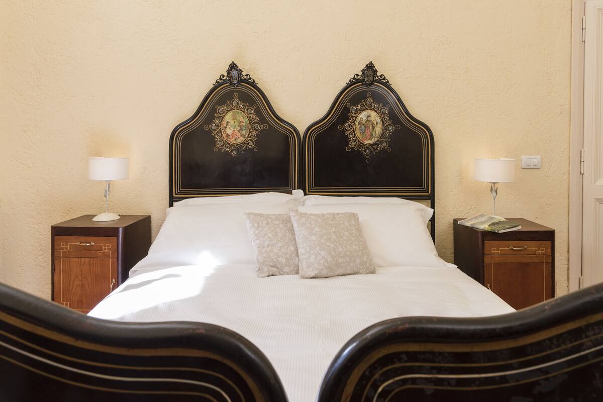 A bedroom with a large bed, two nightstands, and a wooden cabinet.
