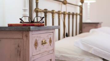 Un lit avec du linge de lit blanc, une table de chevet avec une lampe et une tête de lit décorative en métal.