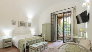 A bedroom with a bed, a wardrobe, a suitcase, a television, and a window with curtains. - Fattoria Pian di Rocca (Castiglione della Pescaia)