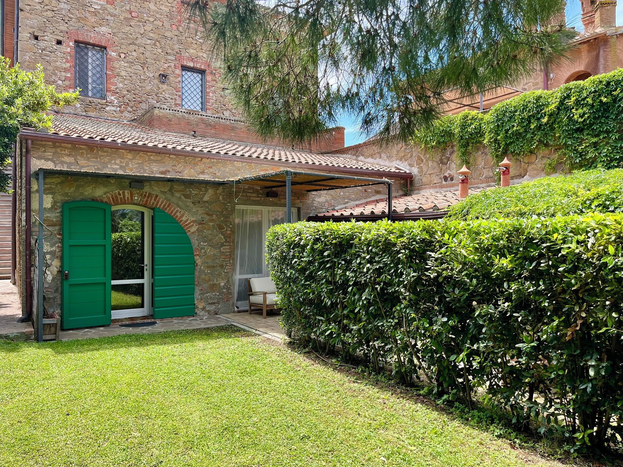 A stone building with a green door and a covered patio area.