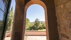 An arched brick structure with a clear view of a green landscape and trees. - Fattoria Pian di Rocca (Castiglione della Pescaia)