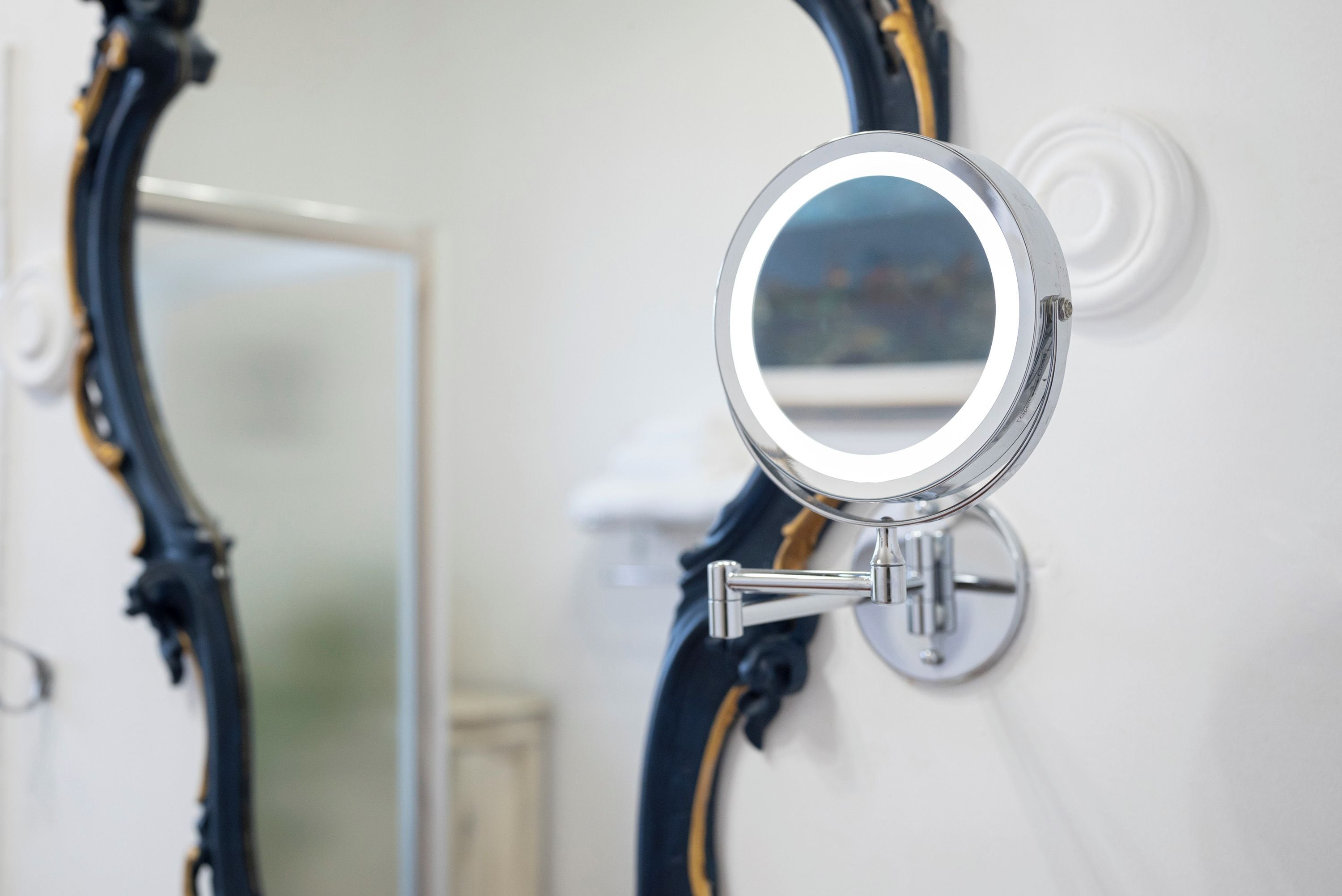 A bathroom mirror with a round frame, mounted on a wall with a white background.