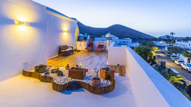 A rooftop terrace with seating, potted plants, and a view of the surrounding area. - Timanfaya Casa Rural (Yaiza)