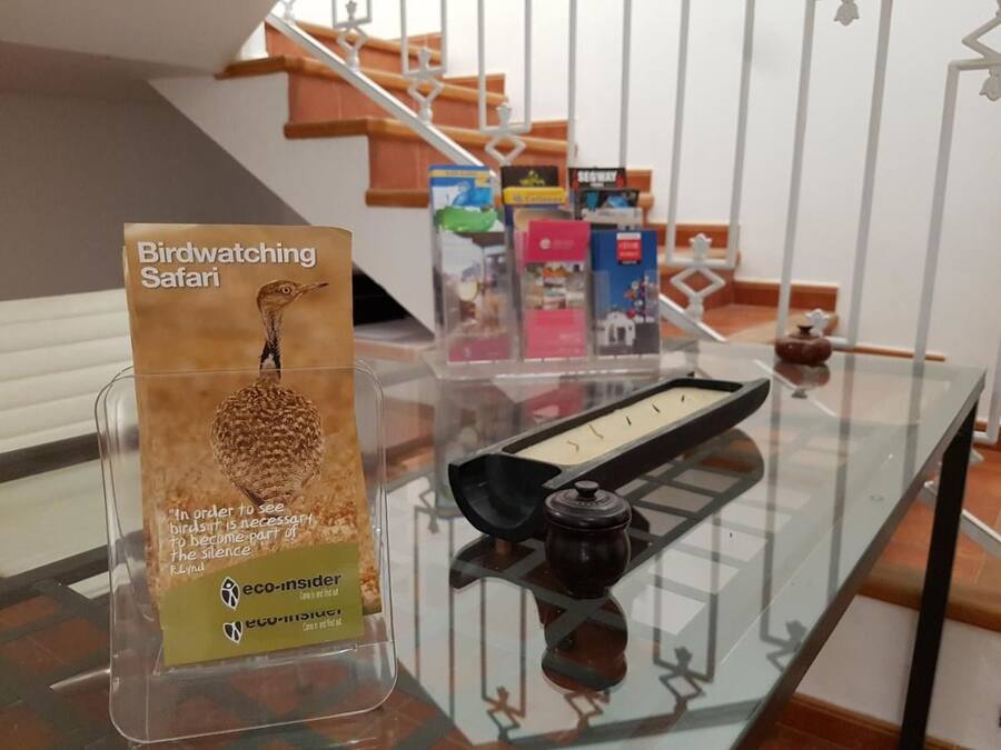 A birdwatching safari sign on a glass table with a view of a staircase and books in the background.