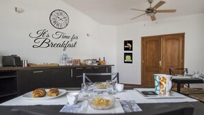 A dining area with a table set for breakfast, a clock, and a wall sign saying "It's Time for Breakfast". - Timanfaya Casa Rural (Yaiza)