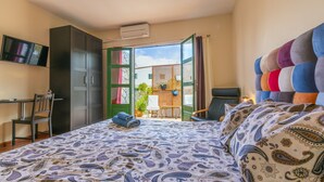 A bedroom with a bed, a desk, a chair, a wardrobe, and an open door leading to a balcony. - Timanfaya Casa Rural (Yaiza)