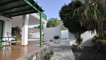 A covered outdoor area with a patio, seating, and potted plants.