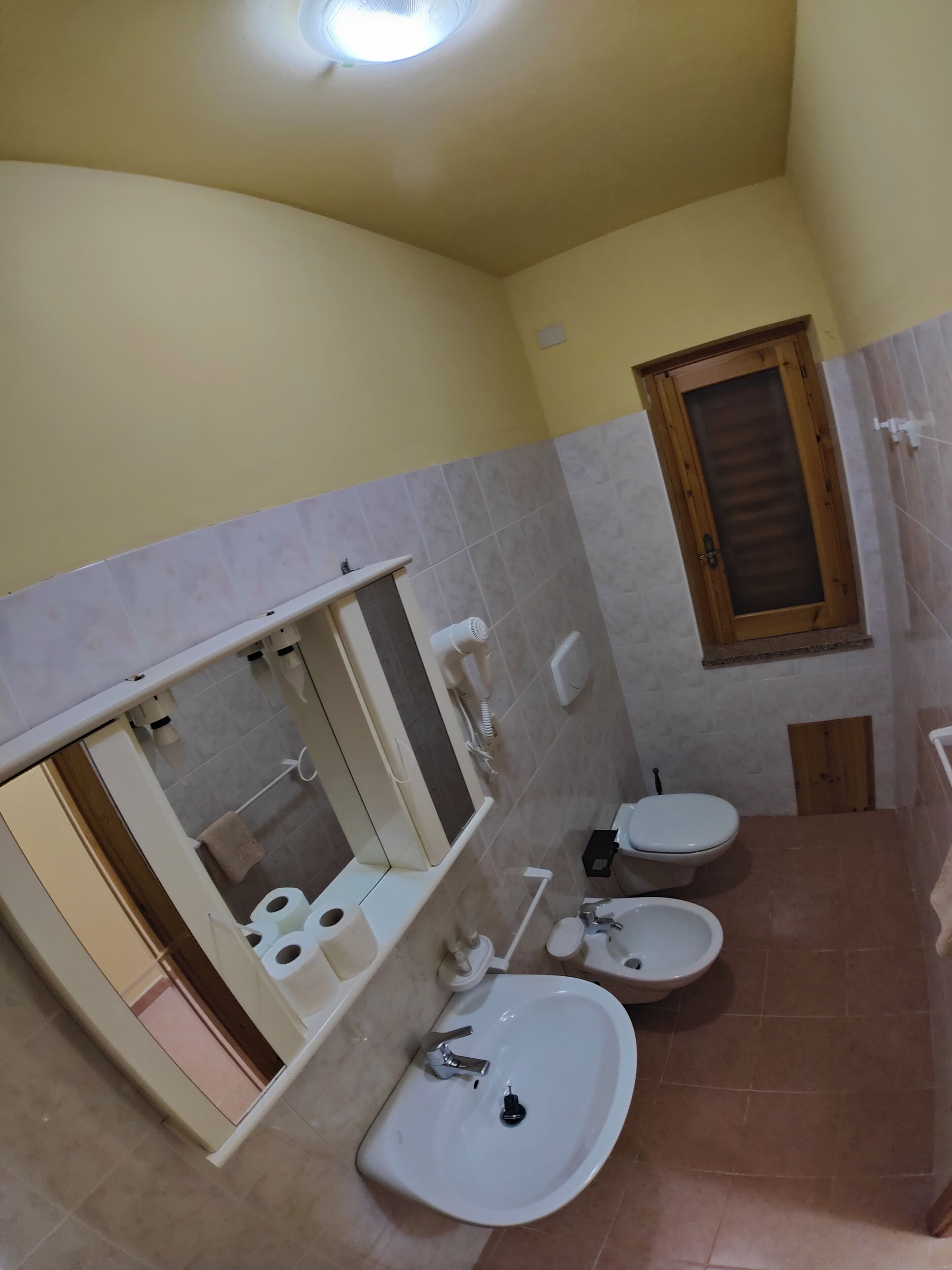 A bathroom with a toilet, bidet, sink, and mirror.