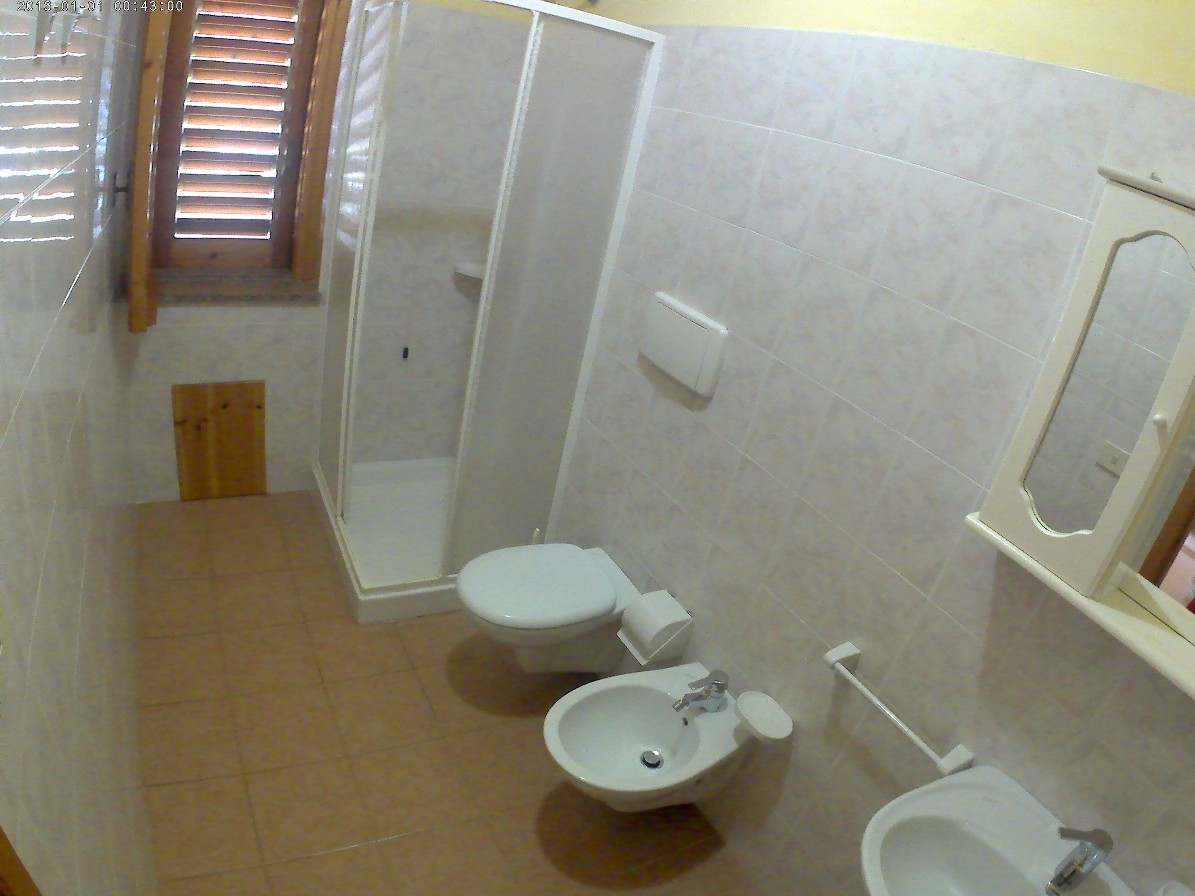 A bathroom with two toilets, a bidet, a sink, and a shower enclosure.