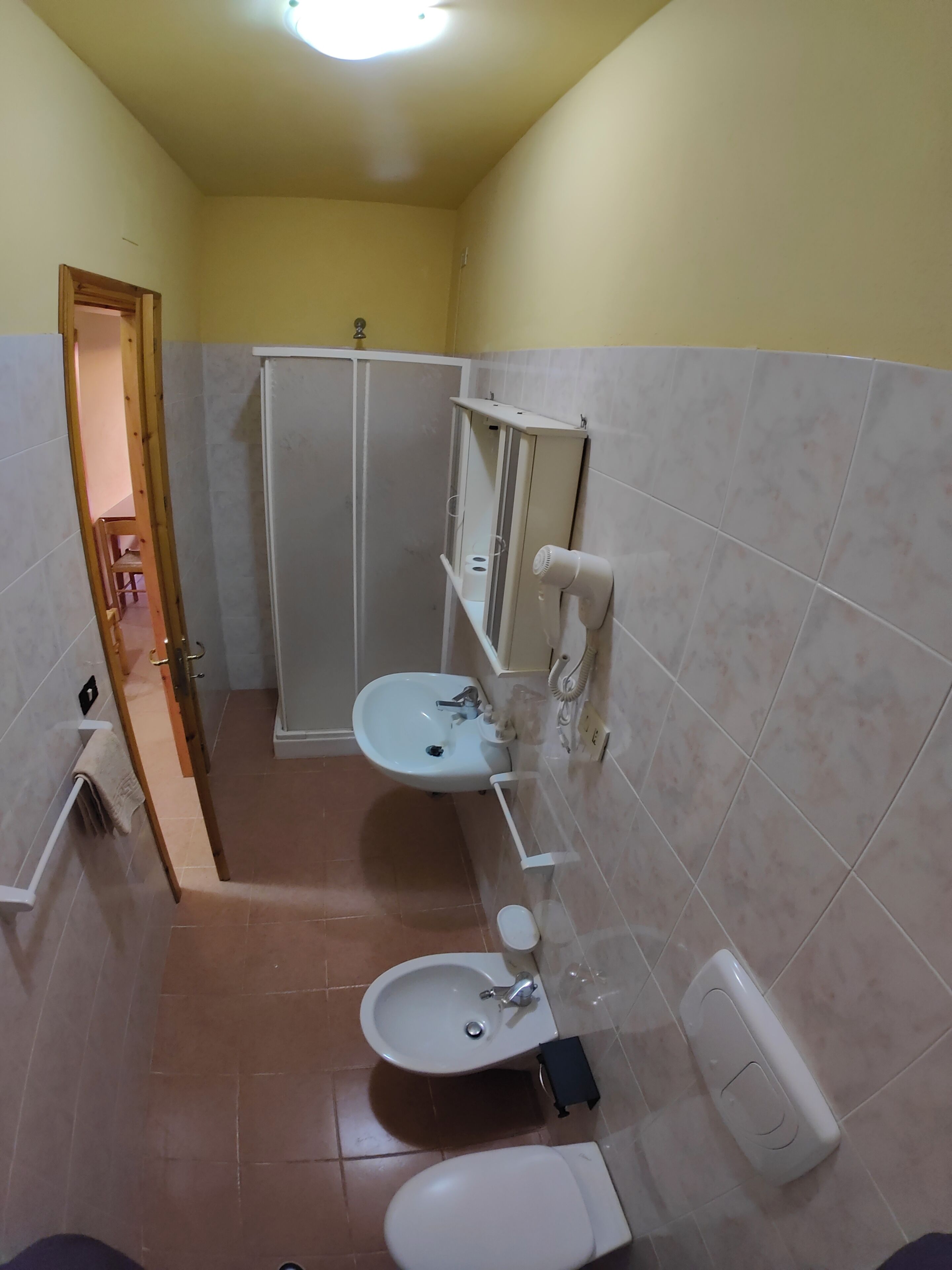 Une salle de bain comprenant des toilettes, un bidet, un lavabo et une douche.