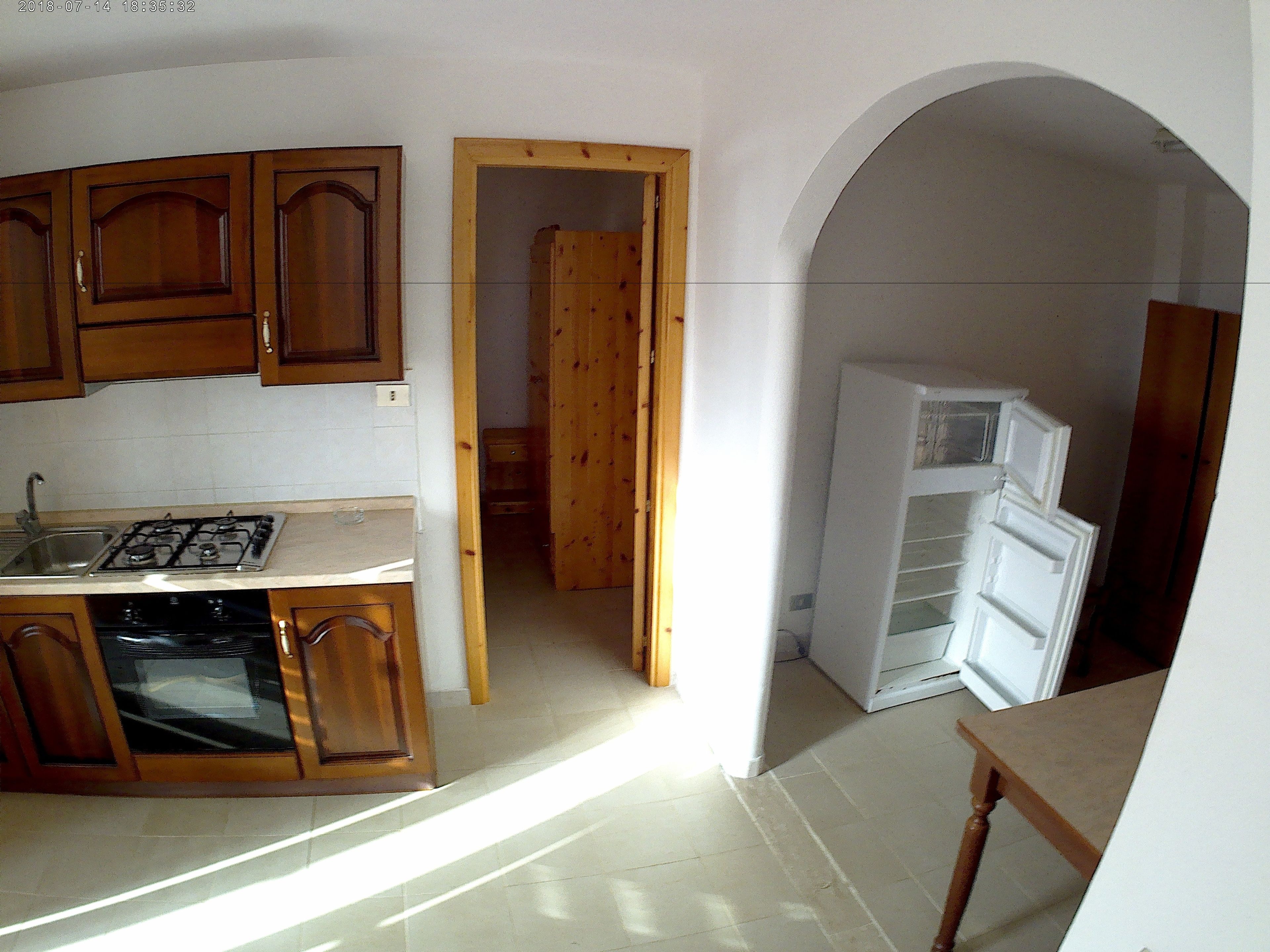 A kitchen with wooden cabinets, a stove, and a refrigerator.