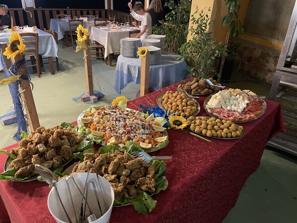Una mesa de buffet con diferentes alimentos y una persona sirviendo.