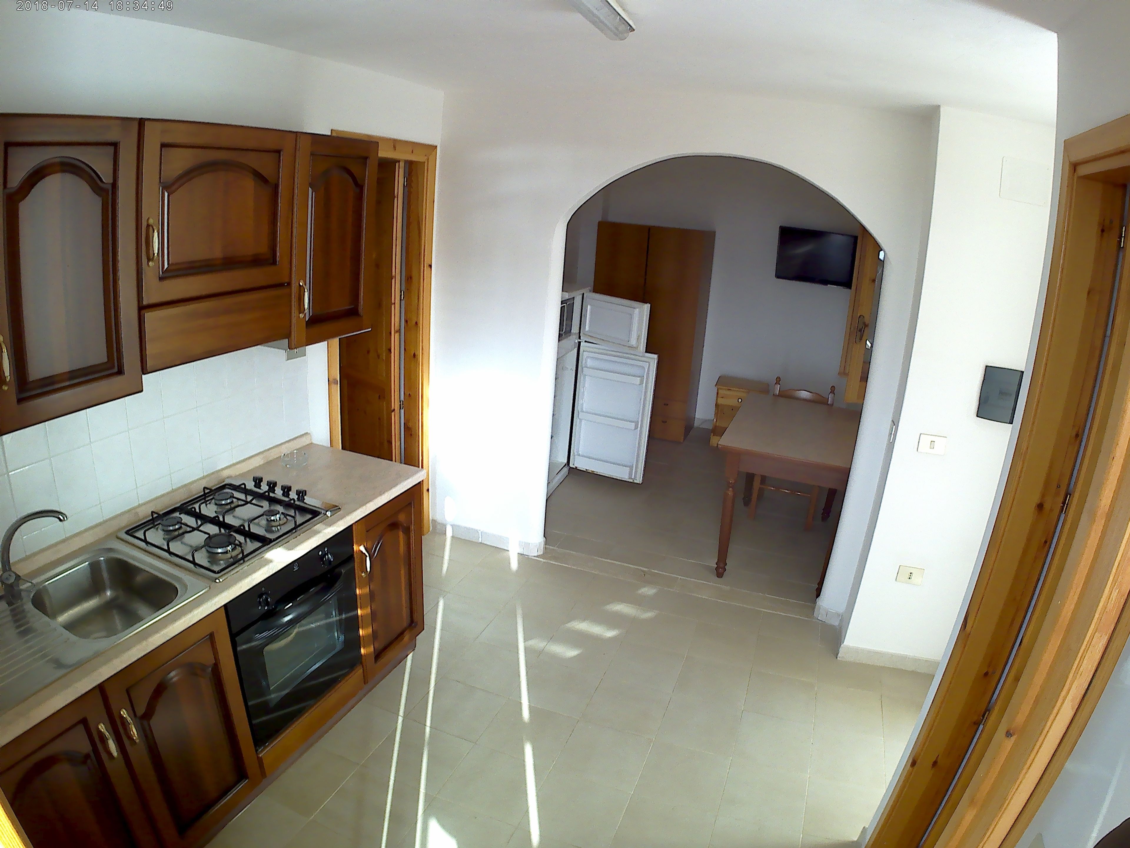 A kitchen with wooden cabinets, a gas stove, and a refrigerator. There is a dining area with a table and chairs.