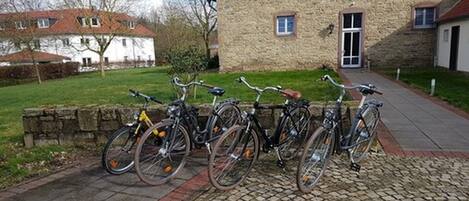 A stone building with a paved entrance and a row of bicycles parked outside.