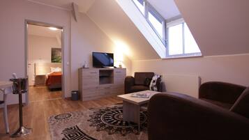 Ein modernes Schlafzimmer im Loft-Stil mit Dachfenster, einem Fernseher, einem Schreibtisch und einer gemütlichen Sitzecke.