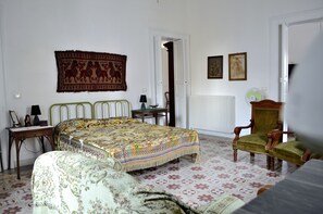Un dormitorio con cama, una silla, una mesa y un radiador.