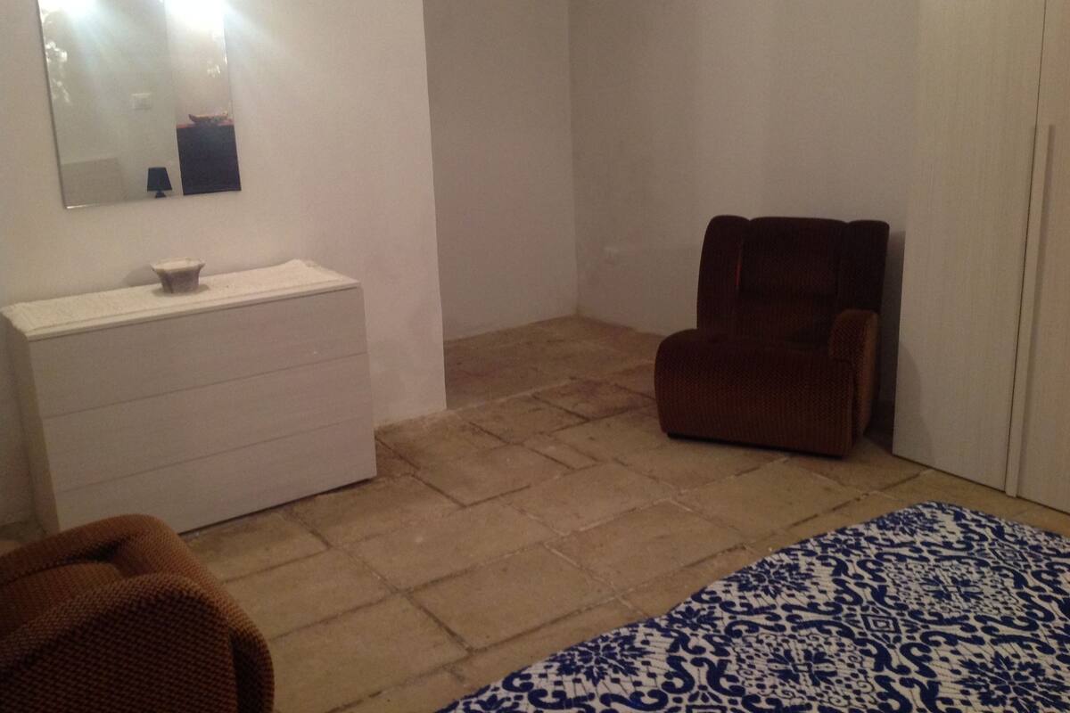 A bedroom with a dresser, a chair, and a patterned rug.