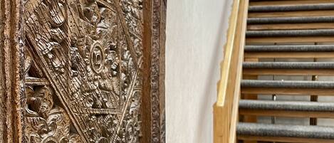 A wooden carved frame with intricate designs, a marble-like countertop, and a staircase with wooden steps.