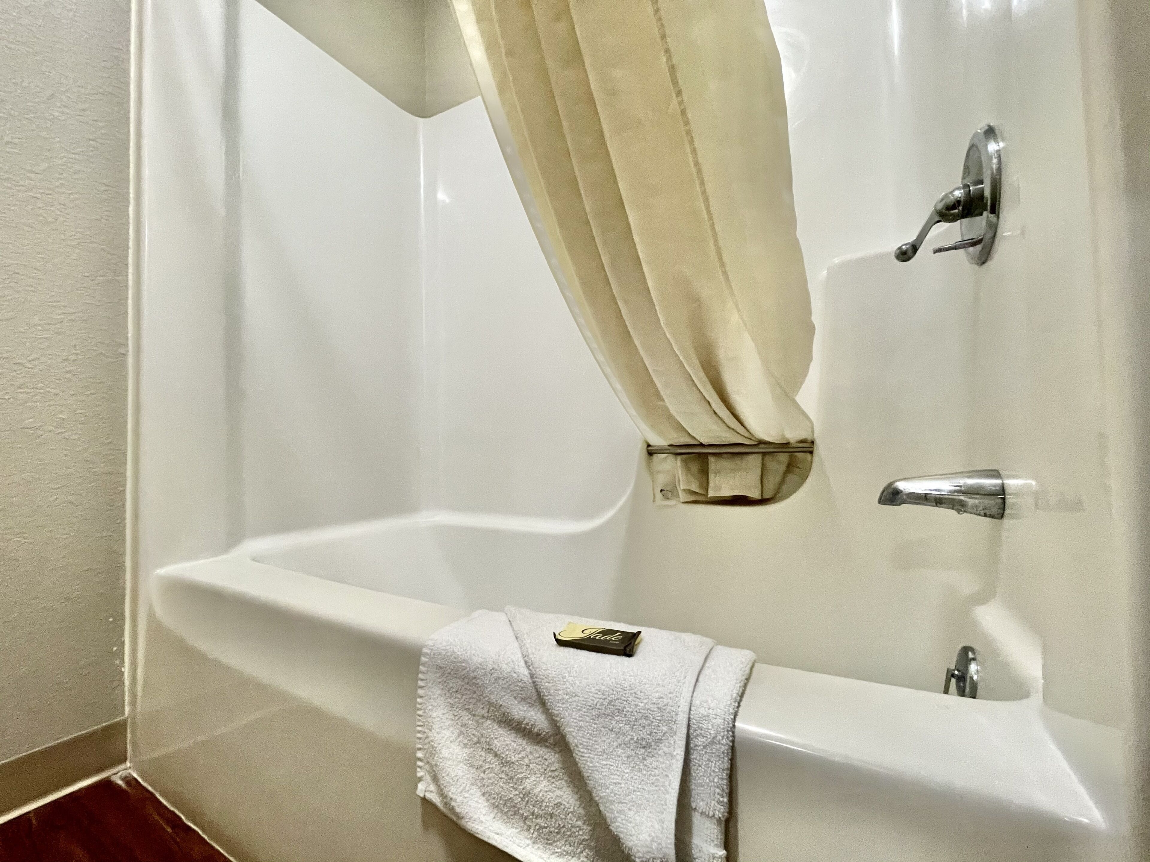 A white bathtub with a towel and a bottle of lotion.