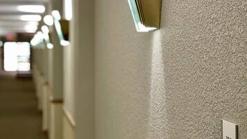 A hallway with a textured wall, a light fixture, and a door with the number 121.