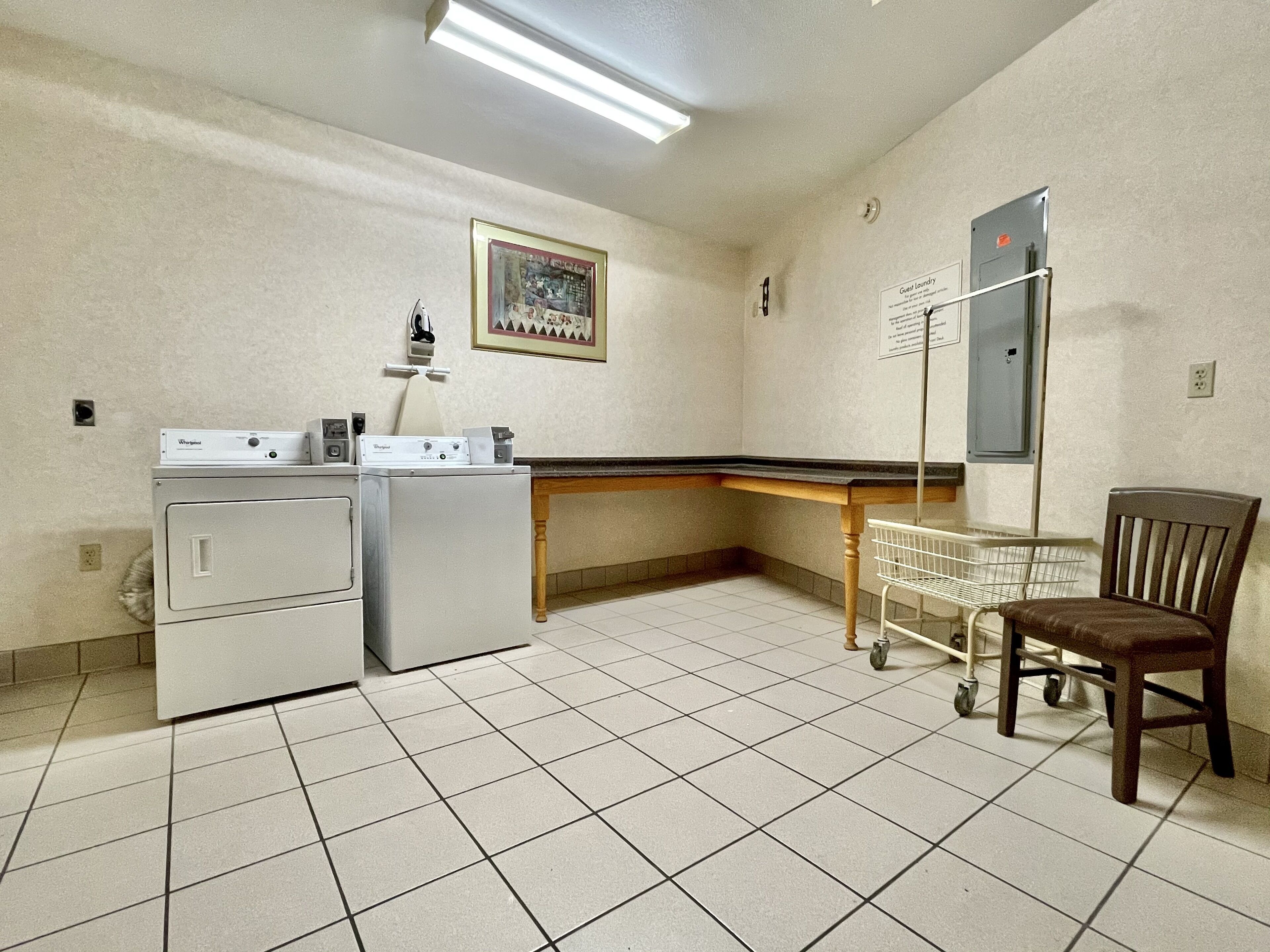 A laundry area with a washer and dryer, a folding station, and a chair.