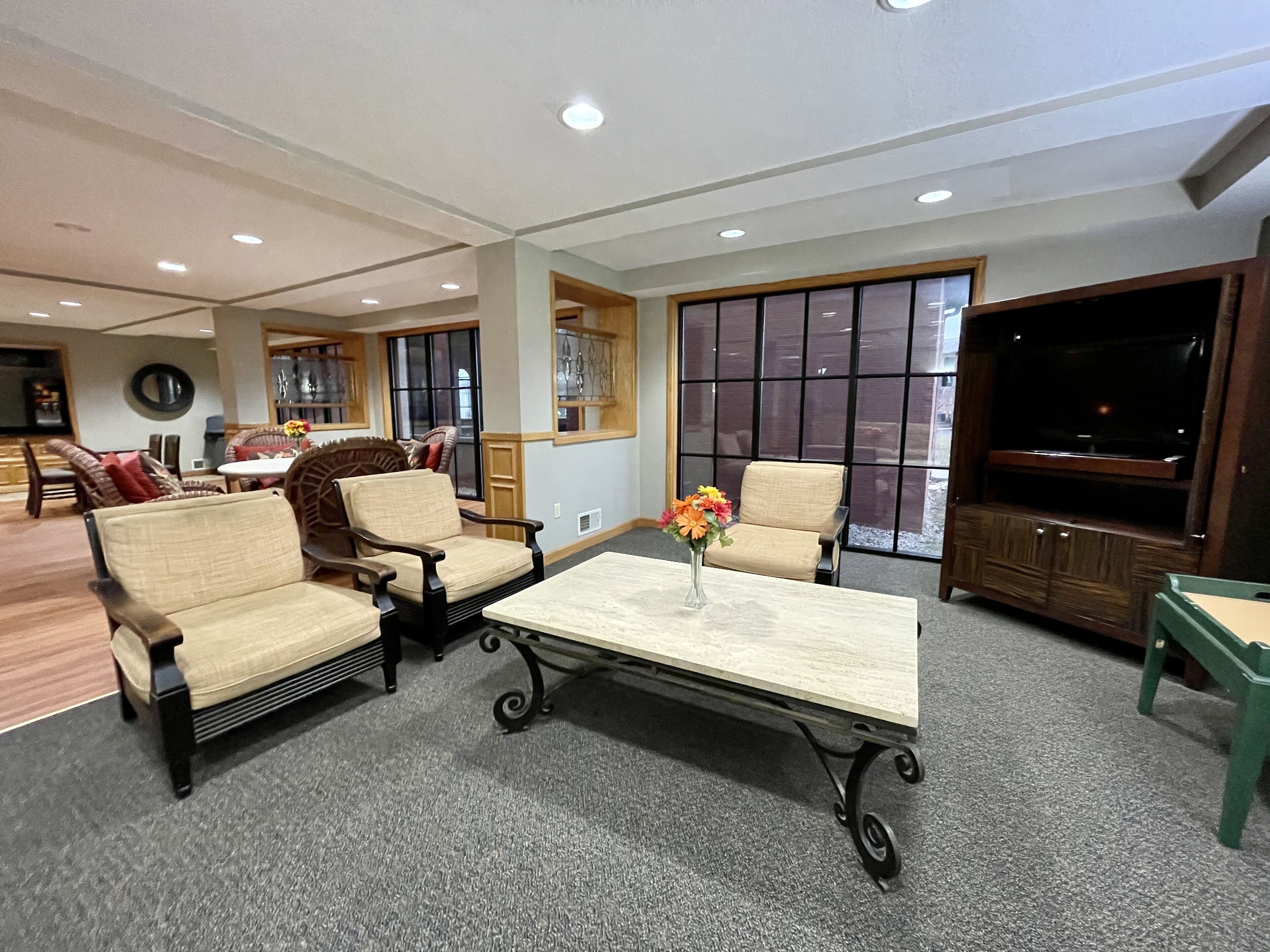 A spacious living room with a large window, a flat-screen TV, and comfortable seating.