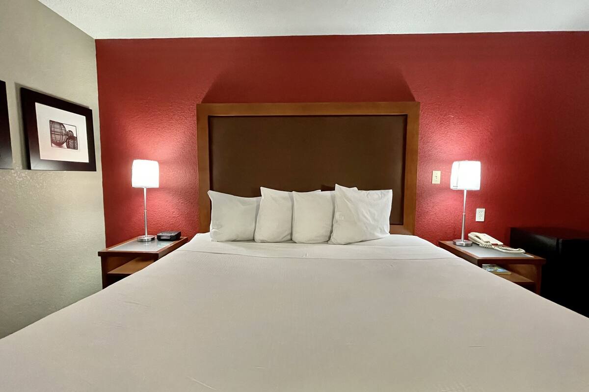 A hotel room with a large bed, two bedside tables with lamps, and a wooden headboard.