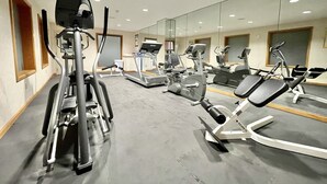 A gym with various exercise machines, a large mirror, and a clean, modern design. - FairBridge Inn & Suites Fort Wayne (Fort Wayne)