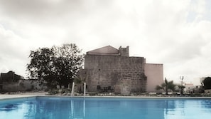 Ein Poolbereich mit einem Steinhaus im Hintergrund.