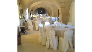 Un salón de banquetes con mesas redondas dispuestas para un evento formal, con manteles y sillas cubiertas en blanco.